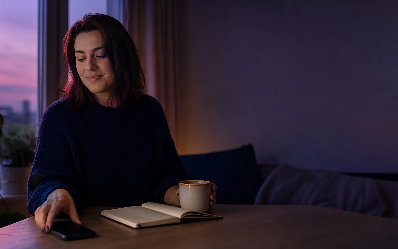Nő nyugodtan félreteszi a telefonját egy esti otthoni beszélgetés után